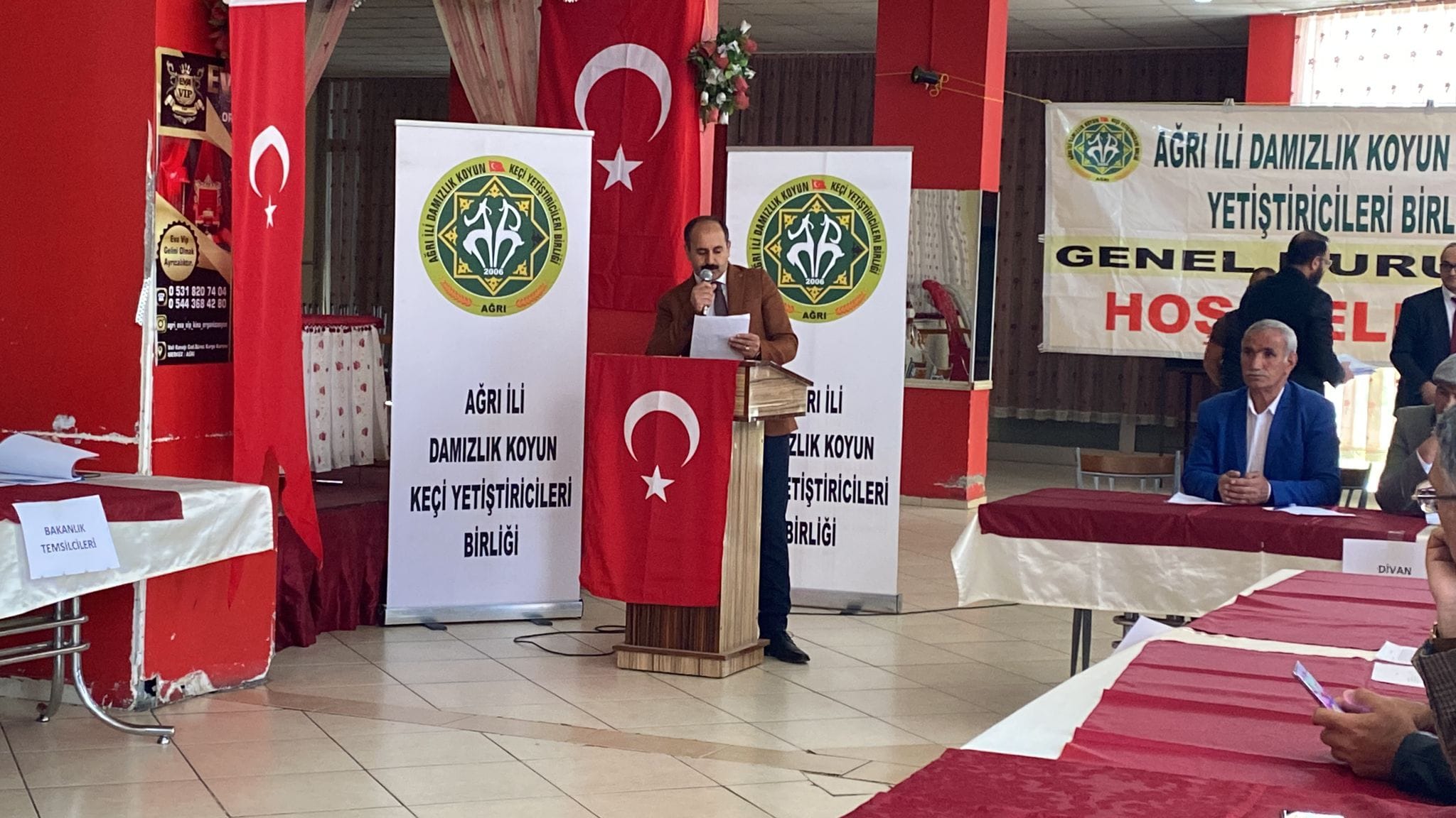 Bir 5 kişi ve şunu diyen bir yazı 'รับตมย 54当4 .4 ل AÔmi ム AФRT AĞRI İLi DAMIZLIK KOYUN YETİŞTİRİCİLERİB BİRL GENEL URU HOS EL 6KAЛR TEMSLOSO AĞRIİLI DAMIZLIK KOYUN KEÇİ YETİŞTİRİCİLERİ BİRLİĞİ _RIİLi İLi ZLIKKOYUN ιικ KOYUN TİŞTİRİCİLERİ BİRLİĞİ DIVAN' görseli olabilir